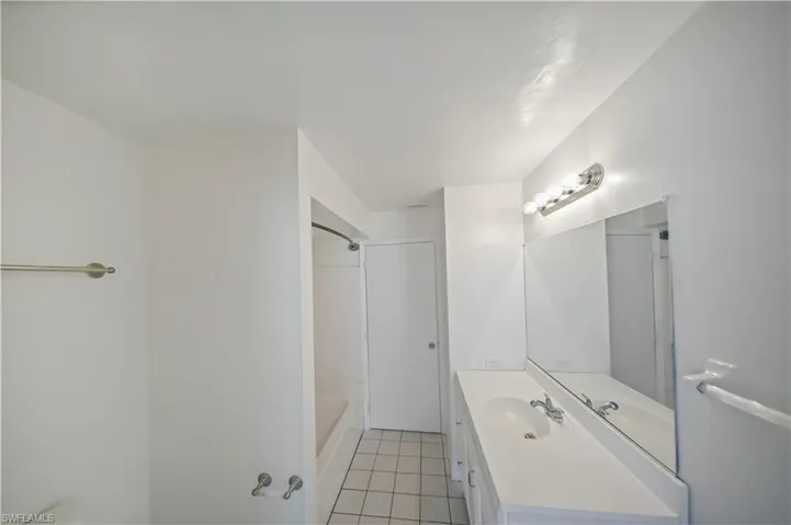 Bright bathroom featuring a vanity with an integrated sink, polished chrome faucet, and a large wall-mounted mirror