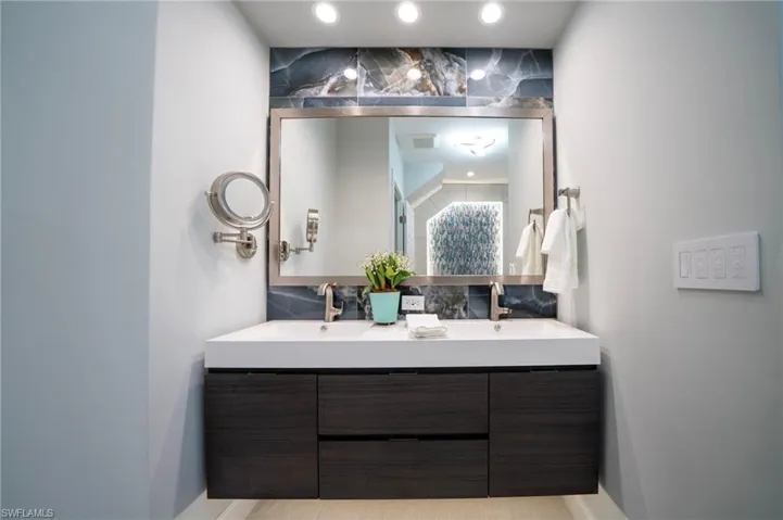 Full bathroom with double vanity, decorative backsplash, and a sink