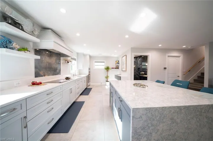 Kitchen featuring light tile patterned floors, a center island, black electric stovetop, open shelves, and recessed lighting