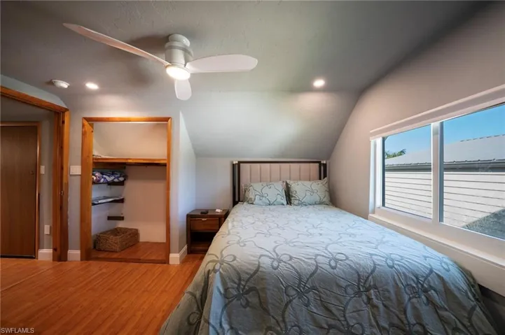Bedroom featuring wood finished floors, a ceiling fan, baseboards, vaulted ceiling, and a spacious closet