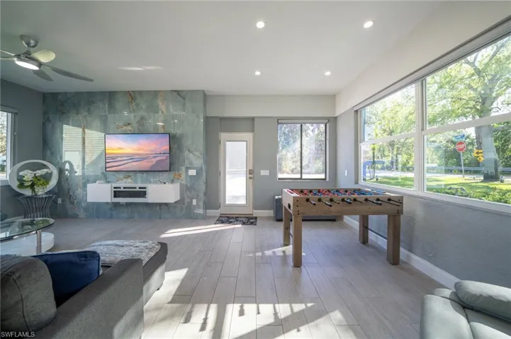 Recreation room with recessed lighting, a healthy amount of sunlight, baseboards, and wood finished floors