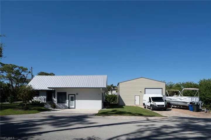 View of front facade featuring an outbuilding, metal roof, a garage, decorative driveway, and a front yard
