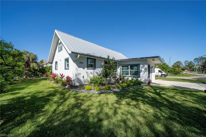View of front facade featuring metal roof, a front yard, and stucco siding