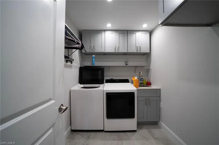 Laundry area featuring recessed lighting, a sink, baseboards, cabinet space, and washing machine and clothes dryer