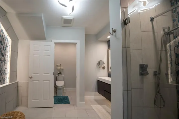 Full bathroom with toilet, tile patterned flooring, a tile shower, and vanity