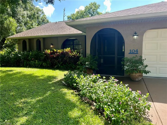 Entrance to property with a garage and a lawn