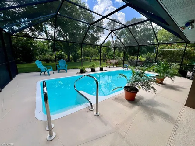 View of swimming pool featuring glass enclosure and a patio