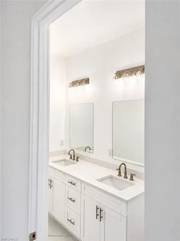 Junior Suite Double vanity featuring white shaker cabinetry, integrated rectangular sinks, and brushed bronze fixtures