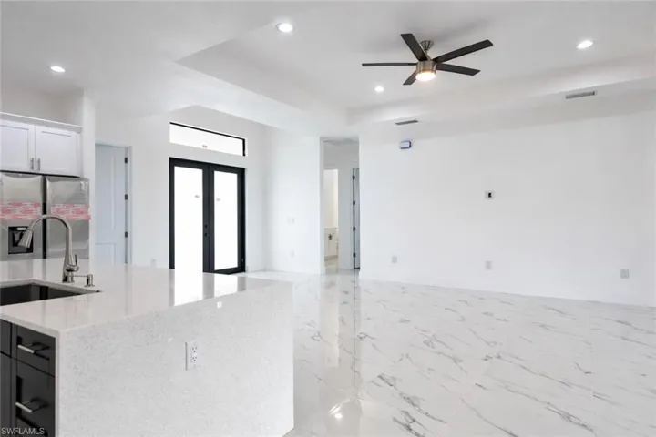 Kitchen featuring stainless steel refrigerator with ice dispenser, light stone countertops, light marble finish flooring, ceiling fan, and french doors