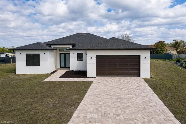Prairie-style house with stucco siding, an attached garage, a shingled roof, decorative driveway, and french doors