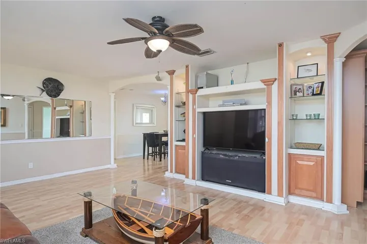 Living room with ceiling fan, decorative columns, and light wood-type flooring