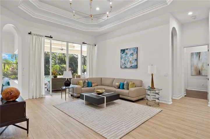 Living room with crown molding, a tray ceiling, and light hardwood / wood-style floors