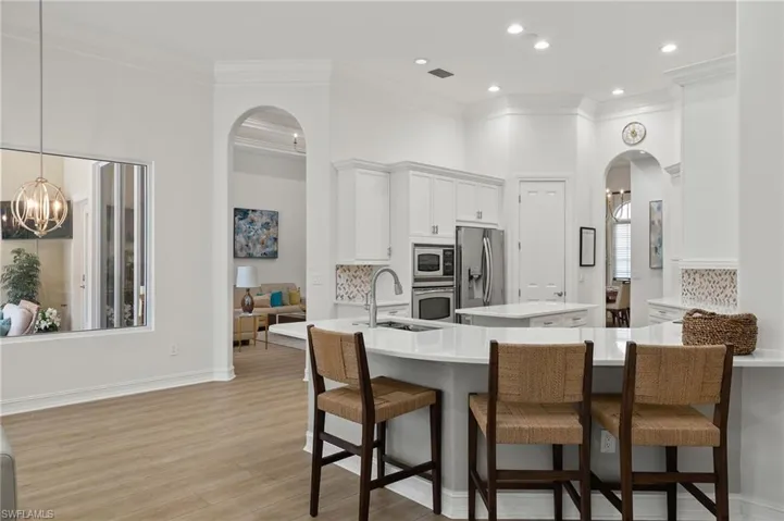 Kitchen with appliances with stainless steel finishes, light hardwood / wood-style flooring, pendant lighting, and tasteful backsplash