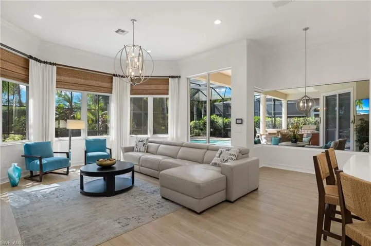 Living room featuring a notable chandelier, ornamental molding, and light hardwood / wood-style flooring