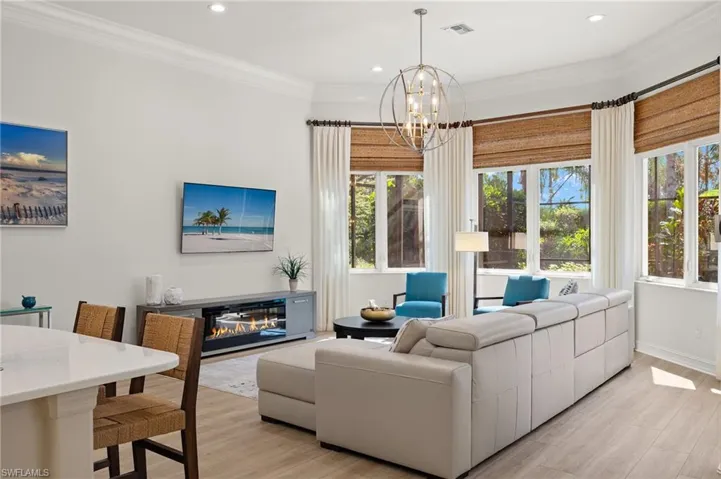 Living room featuring crown molding, light hardwood / wood-style flooring, and a notable chandelier