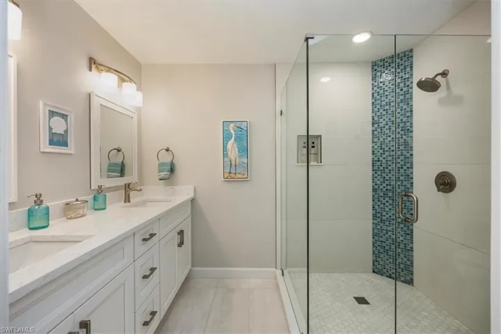 Bathroom with double vanity, a stall shower, and light tile patterned floors