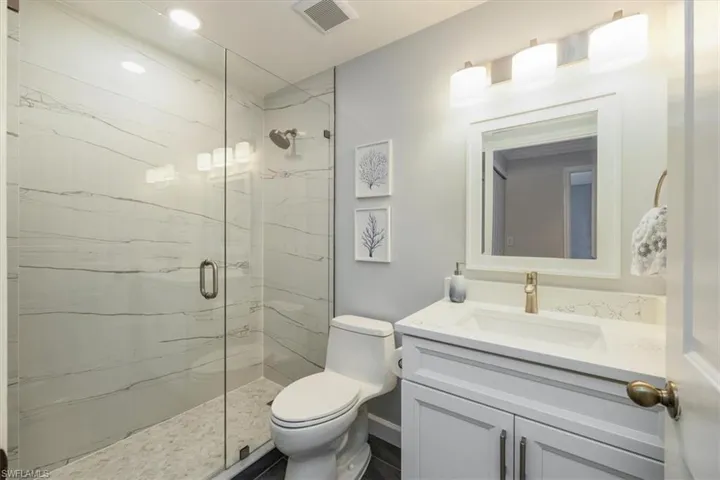 Bathroom featuring vanity and a marble finish shower