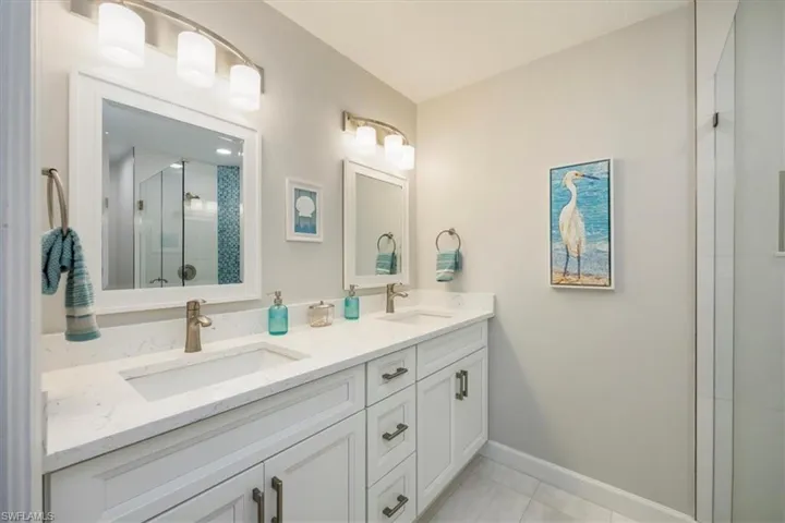 Bathroom featuring double vanity, a stall shower, and light tile patterned flooring