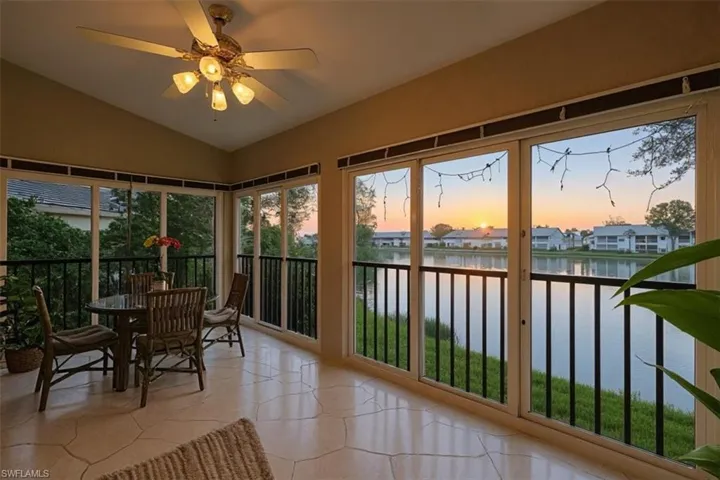 Sunroom / solarium with vaulted ceiling, a water view, a residential view, and tile patterned floors