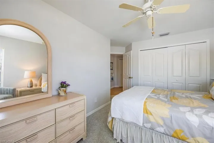 Bedroom with ceiling fan, a closet, and light carpet