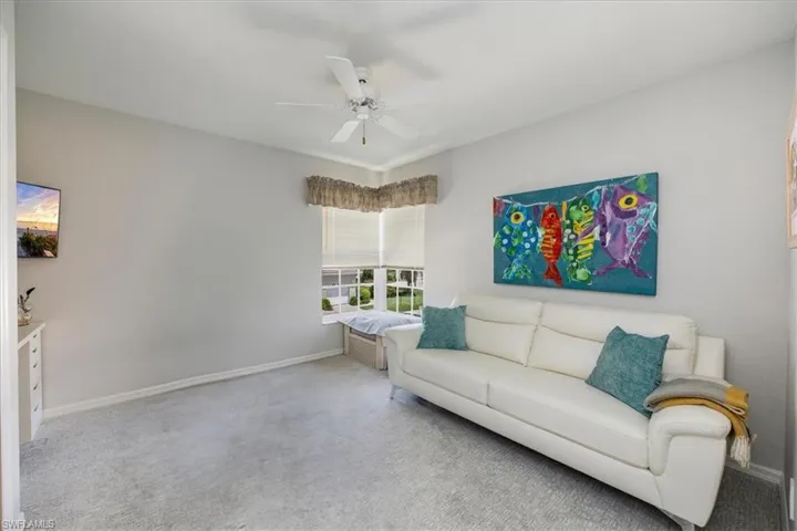 Carpeted living area featuring ceiling fan and baseboards