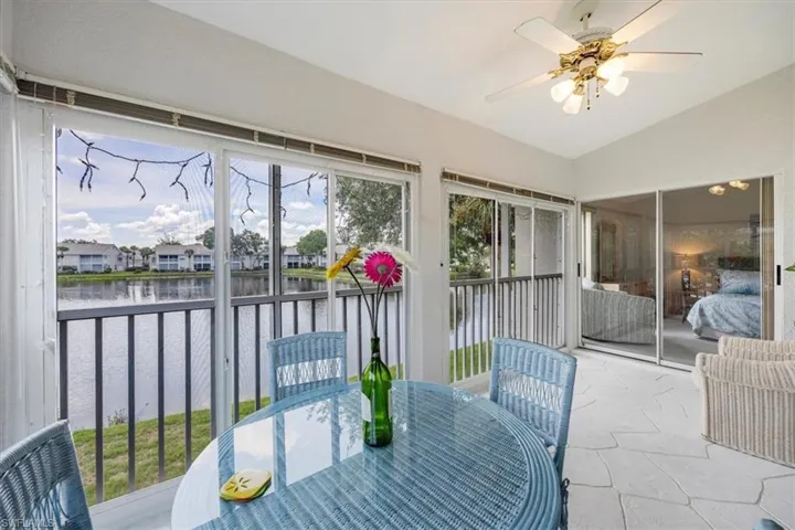 Sunroom / solarium with a ceiling fan, outdoor dining area, lofted ceiling, a water view, and a residential view