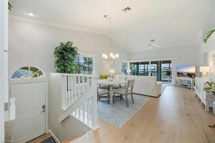 Dining space with vaulted ceiling, ornamental molding, light wood-type flooring, a chandelier, and ceiling fan
