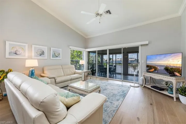 Living area featuring crown molding, wood finished floors, lofted ceiling, and ceiling fan