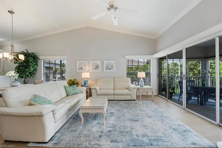 Living area featuring crown molding, wood finished floors, a ceiling fan, a high ceiling, and a chandelier