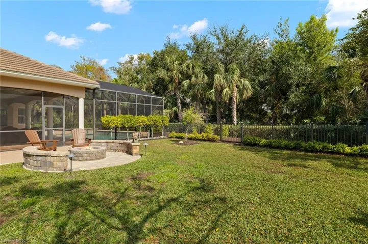 View of yard with a patio area, glass enclosure, and an outdoor fire pit