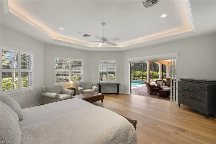 Bedroom featuring a tray ceiling, access to outside, light hardwood / wood-style floors, and ceiling fan