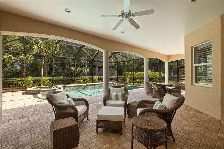 View of patio / terrace featuring a lanai, ceiling fan, and a pool with hot tub