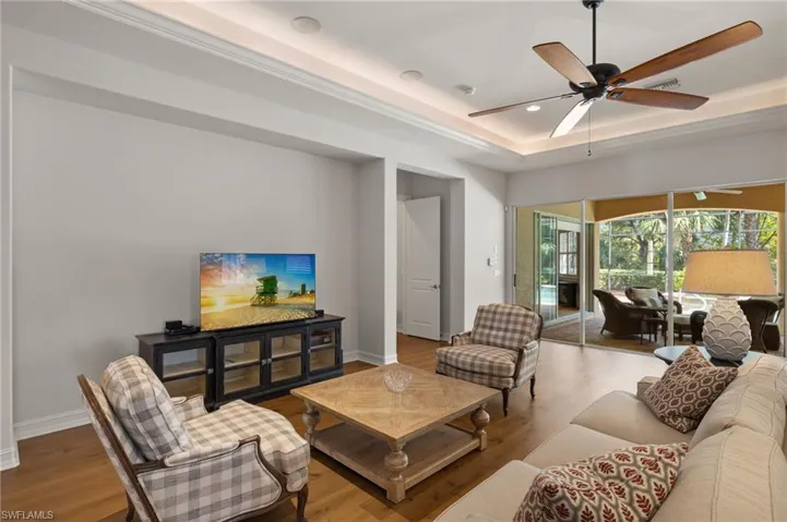 Living room featuring a tray ceiling, light hardwood / wood-style flooring, and ceiling fan