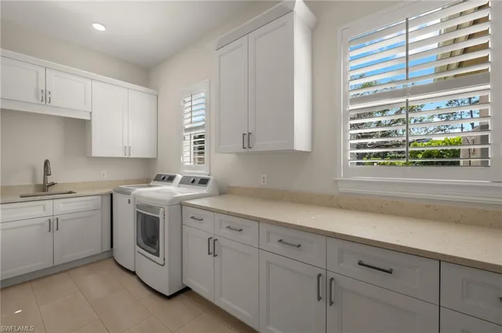 Washroom featuring sink, cabinets, independent washer and dryer, and light tile patterned flooring