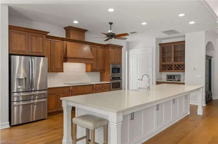 Kitchen featuring a breakfast bar, sink, light wood-type flooring, appliances with stainless steel finishes, and an island with sink