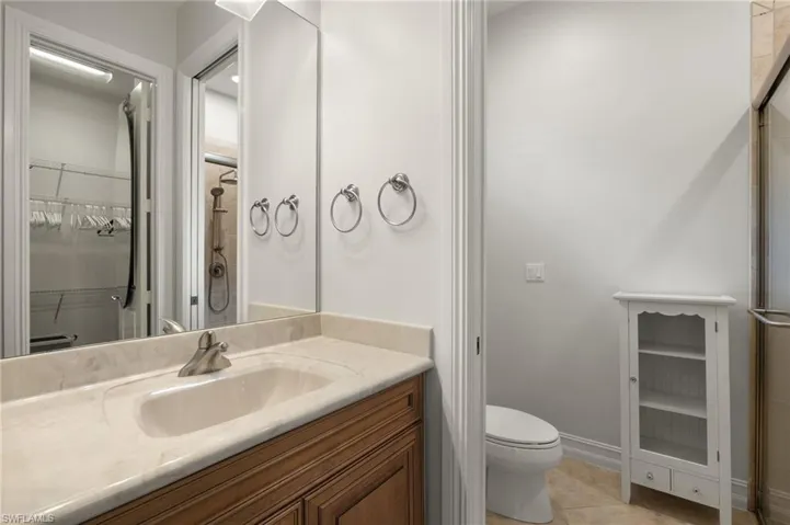 Bathroom featuring a shower with door, vanity, tile patterned floors, and toilet