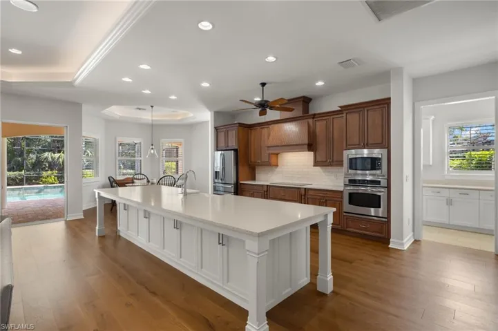 Kitchen featuring white cabinets, a kitchen bar, custom exhaust hood, a large island, and stainless steel appliances