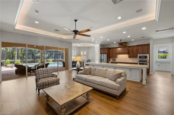 Living room featuring sink, a tray ceiling, a wealth of natural light, and light hardwood / wood-style floors