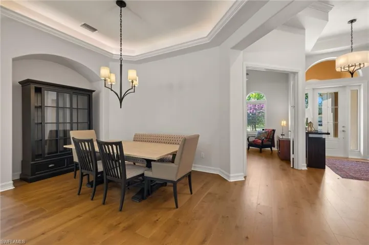 Dining room featuring ornamental molding, light hardwood / wood-style flooring, an inviting chandelier, and a tray ceiling