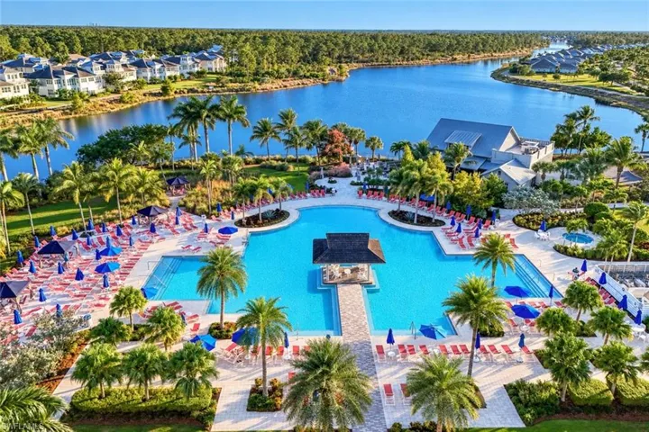 Expansive outdoor pool deck featuring a large resort-style pool, multiple lounge chairs, and mature palm trees