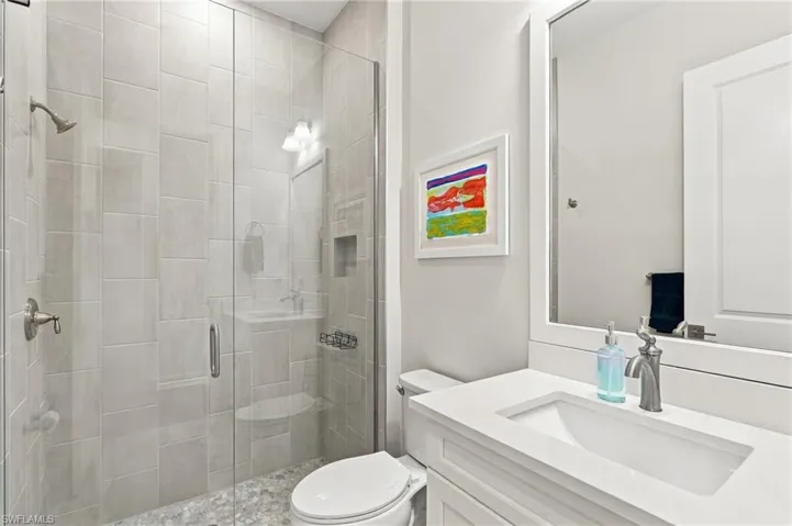 Glass-enclosed shower with a tiled surround, built-in shelving, and a pebbled floor