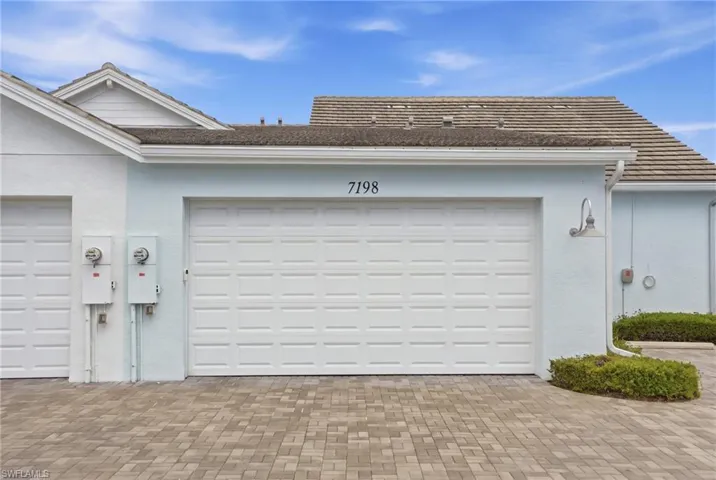 Two-car garage with panel-style doors, paver driveway, stucco exterior, and tiled roof
