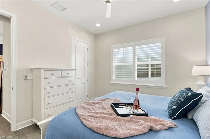 Recessed lighting, ceiling fan, white paneled door, window with plantation shutters, and wood-finish flooring