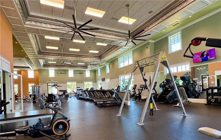 Spacious fitness center featuring various exercise equipment, high ceilings with decorative molding, large windows, and recessed lighting