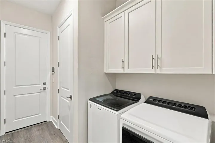 White shaker-style cabinetry, wood-finish flooring, and white paneled doors