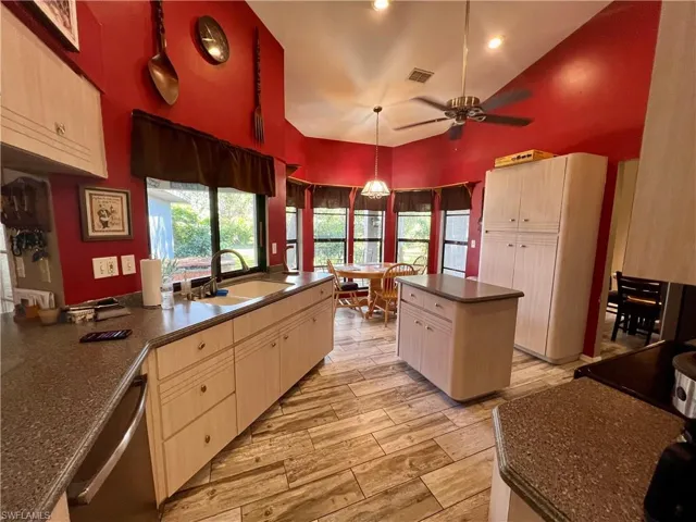 Kitchen featuring wood plank tile floors, sink, decorative light fixtures, stainless steel dishwasher, and a center island