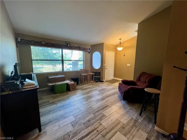 Living room featuring light wood plank tile flooring and vaulted ceiling