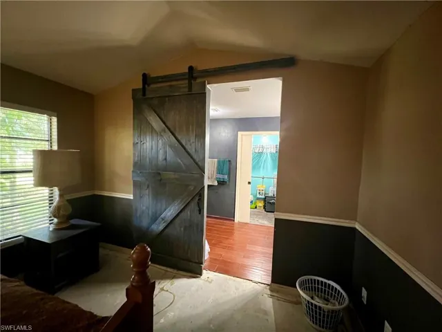 Primary bedroom with barn door entrance to primary bathroom.