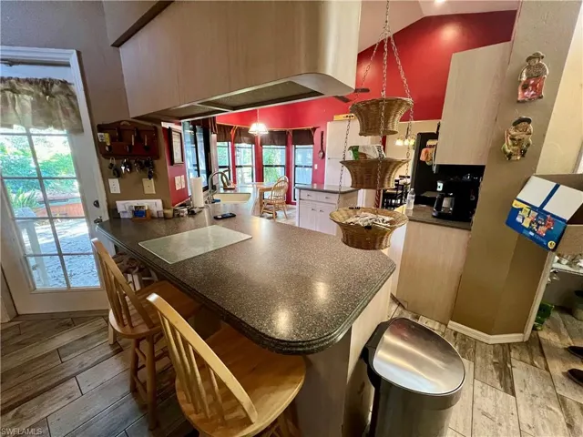 Kitchen featuring kitchen peninsula, a healthy amount of sunlight, a breakfast bar, wood plank tile floors