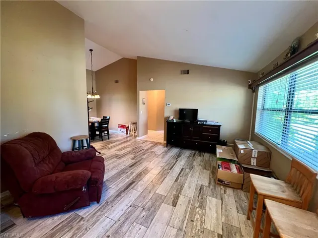 Living room featuring high vaulted ceiling, wood plank tile floors